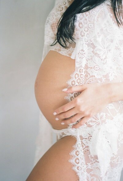 Pregnant woman holding belly in lace dress to show what to expect at san francisco maternity photography session