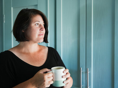 Meg Bogart, founder of Closing Photos, standing in kitchen with mug.