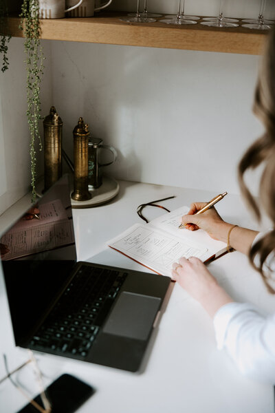 SEO copywriter Erika Fitzgerald sketching website wireframes in a notebook next to an open laptop with draft web copy
