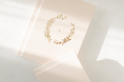 Flatlay image of two linen heirloom photo albums with a gold-embossed crest on the cover, representing premium photo products offered in Kansas City.