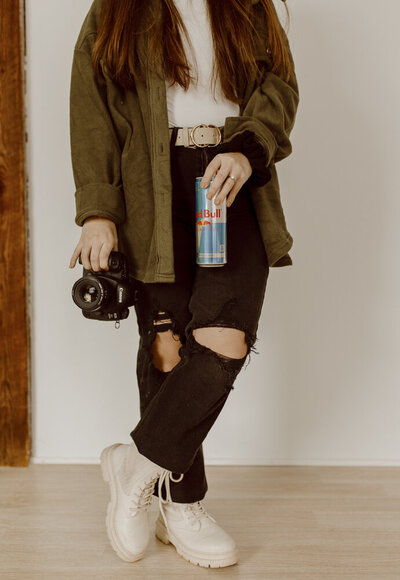 Photographer holds red bull and camera in hands.