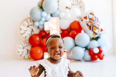 woman and baby on bed laughing with white balloons