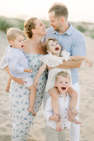 image of a family with 3 children laughing and playing during family photos on the beach in virginia beach