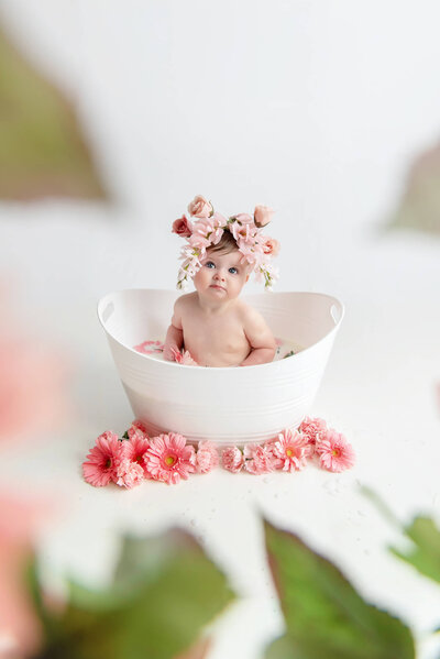 Sweet 1 year old girl sitting in a milk bath with pink flower crown for her portrait session in Burlington, Ontario.