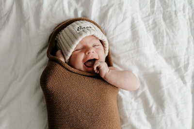 newborn baby met handje bij de mond