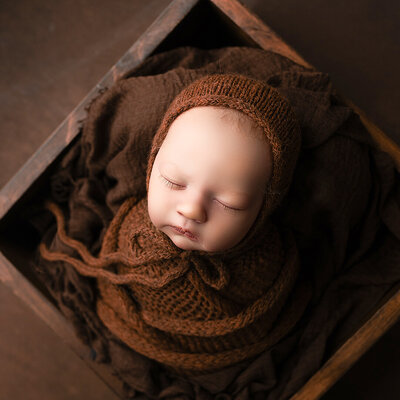 A baby girl is sleeping in a box, wrapped all in brown, in Warwick NY