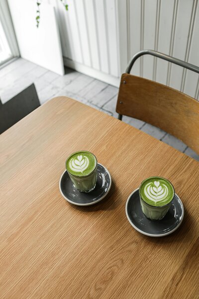 Two matcha lattes on a wood table — representing Meghan’s slow travel philosophy and favorite expat cafes featured on Leaving Main Street