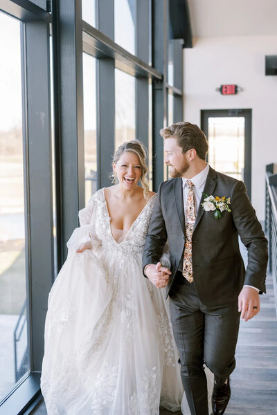 Bride and groom smiling going into their reception with the bride's hair styled by Promise Bridal Artistry