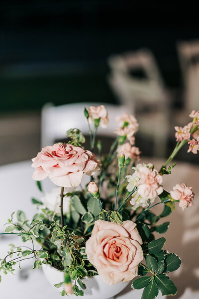 greenery in vase with pink flowers on white table