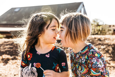 sibling sisters kissing noses during a family photo session in san francisco.