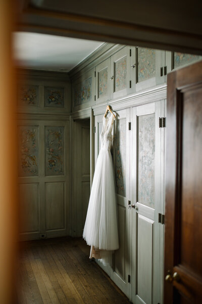 brides dress hanging on green hand painted cabinetry inside villa terrace decorative arts museum in milwaukee wisconsin