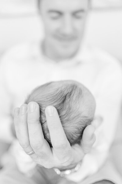 dad holding baby's head during lifestyle newborn photos in Fairfax, Virginia, taken by a Northern VA family photographer