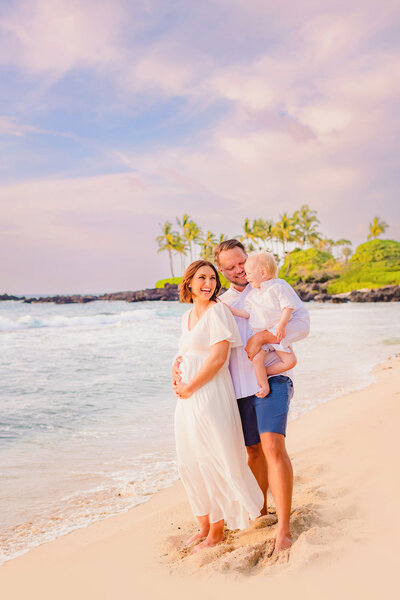 Pregnant woman on the beach on Maui with her partner and toddler