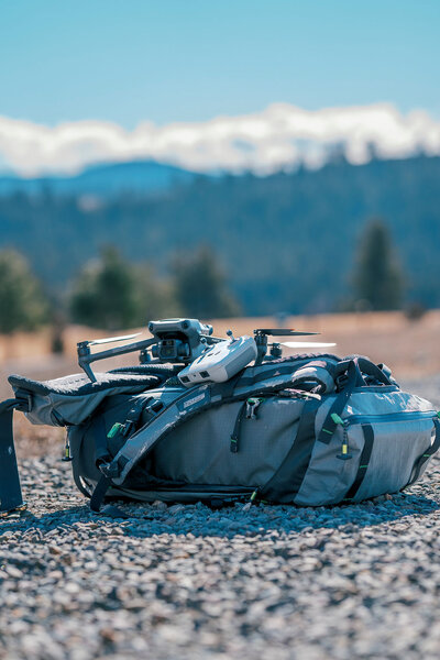 Drone and camera backpack staged outdoors in the Montana wilderness, showcasing Joseph Mayden’s aerial photography and videography equipment for remote shoots.