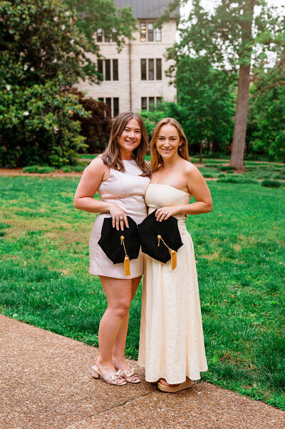 Two senior girls holding their Master caps in the Vanderbilt campus