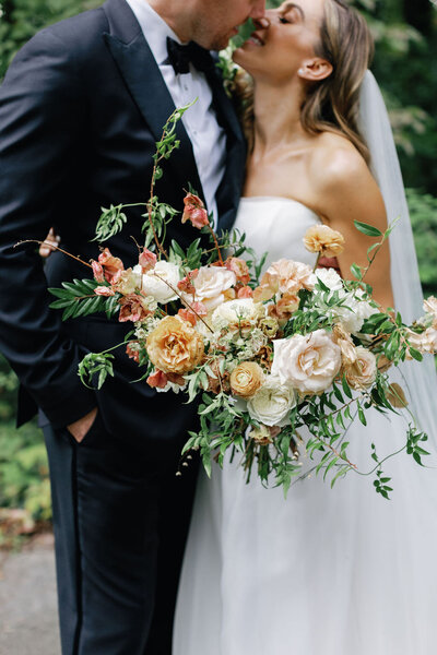 Lush bridal bouquet with dusty rose and copper flowers including garden roses, ranunculus, dried flowers, and natural greenery. Wedding floral design at RT Lodge by Rosemary and Finch in Nashville, TN.