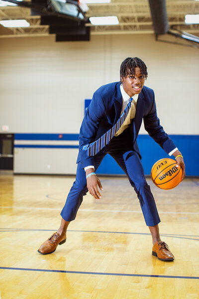 Young man dribbling a basketball in suit and tie