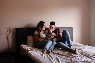 babyshoot papa mama en baby newborn zitten op bed en lachen