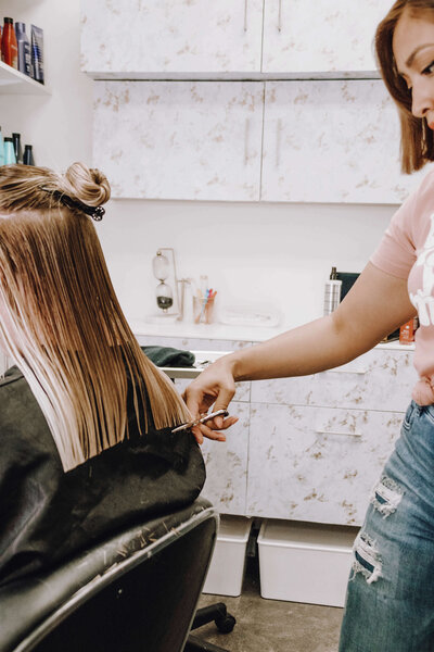 Gabriela Arista, a North Austin hairstylist, cutting hair on a wet balayage client