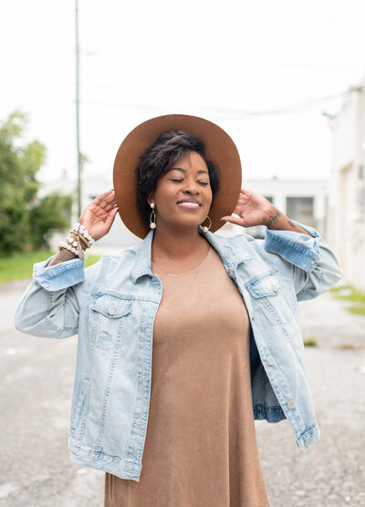 A woman wearing a stylish brown hat looks joyful and carefree