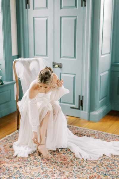 Bride with off the shoulder gown adjusting shoes