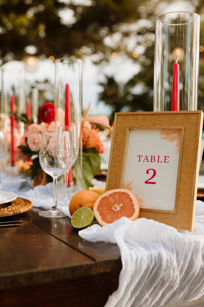 Vibrant tablescape at the iconic Mauna Kea Resort, featuring fresh fruit and pops of bright pink, with rentals by Big Island Tents and flowers by Flower Me Pretty Hawaii, creating a luxurious and tropical setting for a destination wedding in Hawaii.