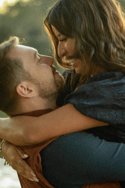 A romantic shot of a couple as the groom-to-be lifts his fiancé, capturing their love near a serene Houston lake