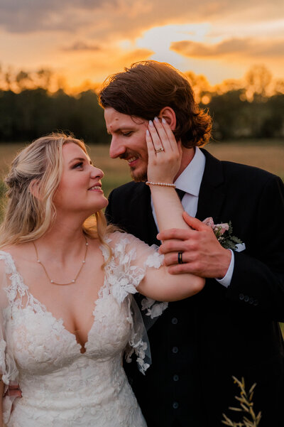 A couple poses for the camera looking at one another during golden hour.