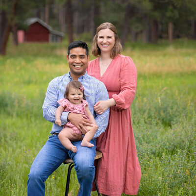 young family standing in a field holding their young baby in Pueblo Colorado
