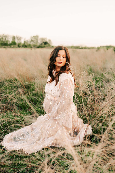 pregnant mom kneeling in field closing eyes captured by Joplin MO motherhood and family photographer Jessica Kennedy of The XO Photography
