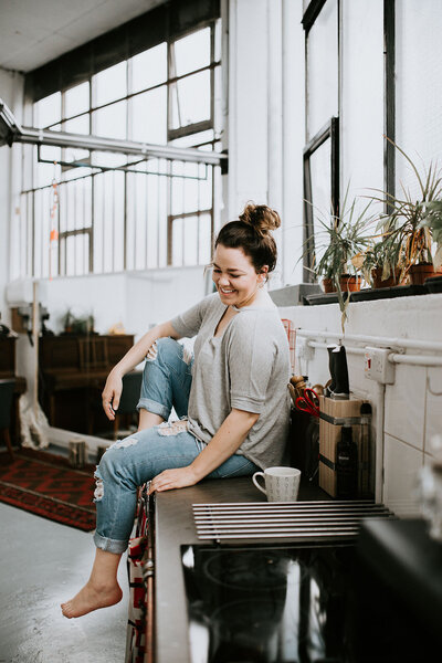 Woman smiles while sitting on countertop.