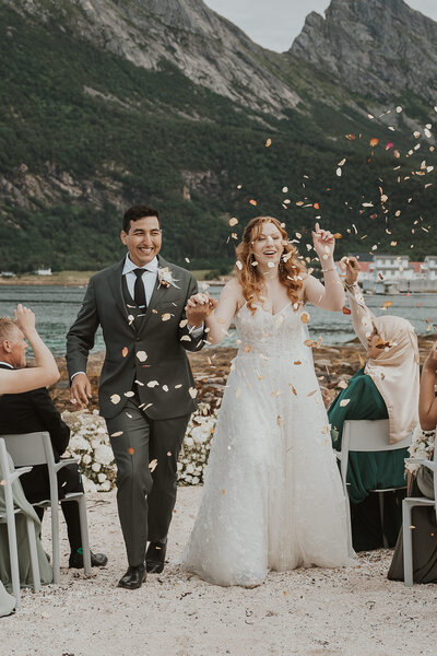 Wedding couple getting married on a beach in lofoten and getting confetti thrown in the air.