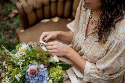 Pittsburgh wedding florist Heavenly Blooms sitting down at a table creating a floral arrangement