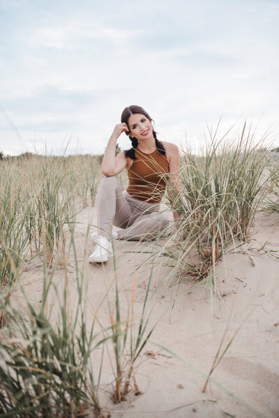 The Bride's List founder Stephanie sitting on the beach in tan athletic gear and white sneakers.