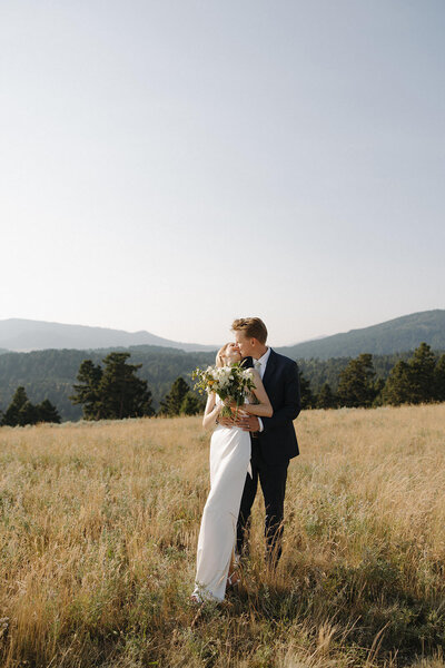 couple standing on bozeman mountain top embracing in a kiss