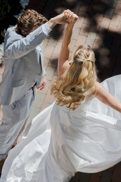 Bride twirling with groom in sunlight at Raleigh, North Carolina wedding, captured in joyful photo and video by Moments by Hiba.