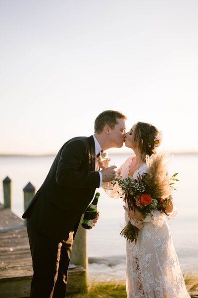 Bride and groom kiss waterfront