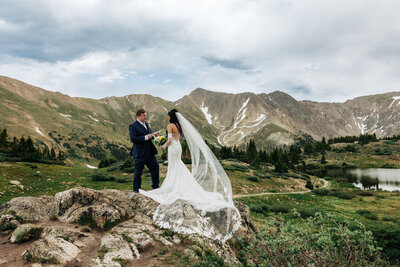 there is a big wide view of a mountain and a trail. the couple is very small in the frame but they're walking up a trail together