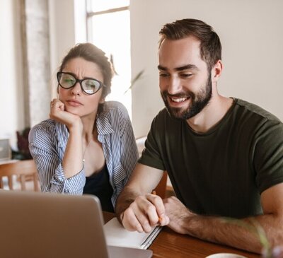Couple sitting together at home during an online marriage counseling session, showing curiosity and hope as they work on improving their relationship.
