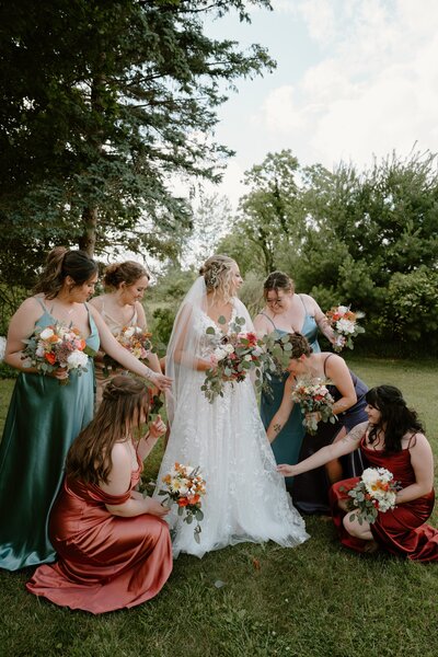 bride with her bridesmaids wearing burnt orange and green dresses
