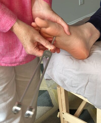 Biofield Tuning session. Applying a weighted tuning fork to client's K1 point on the right foot during the opening sequence.  