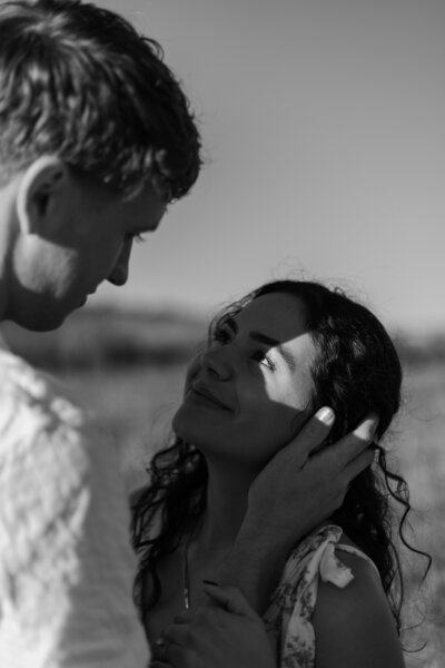 David holding Elizabeth's cheek, with the light shining on her eye, in black and white.