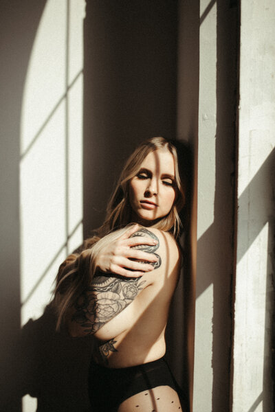 woman holding herself posing by window