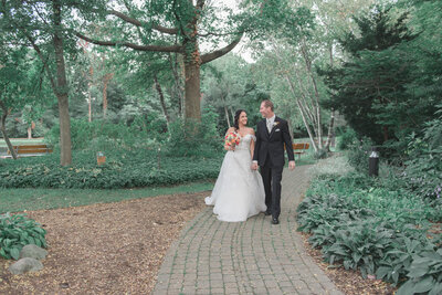 couple holding hands walking down cobble stone path looking at each other