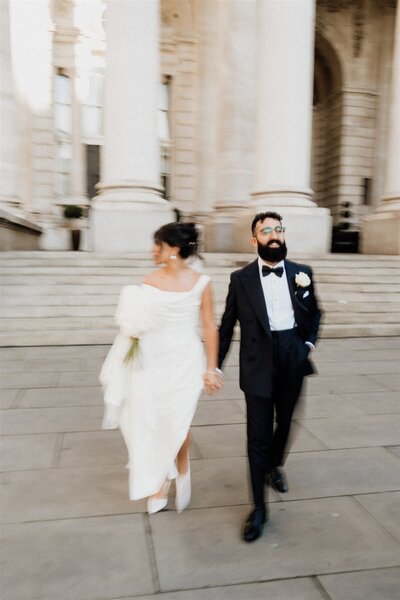blurry modern wedding photo of bride and groom in tux walking in the city of london