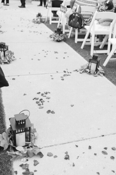 A wedding aisle lined with lanterns and rose petals strewn about.