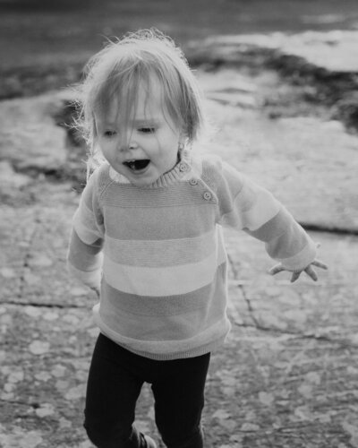 2 year old child running arms in the air and smiling at a park in Helsinki