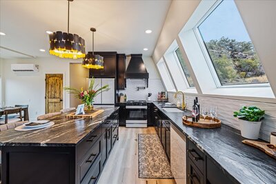 The nearly completed Perrine Hideaway A-frame cabin, featuring a black metal roof, large glass windows, and a rugged canyon backdrop