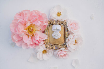 Wedding rings in a box surrounded by pink flowers