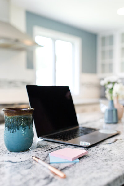 laptop of showit designer on kitchen island next to a coffee mug